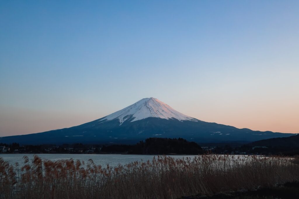 a snow covered mountain with a lake in the foreground